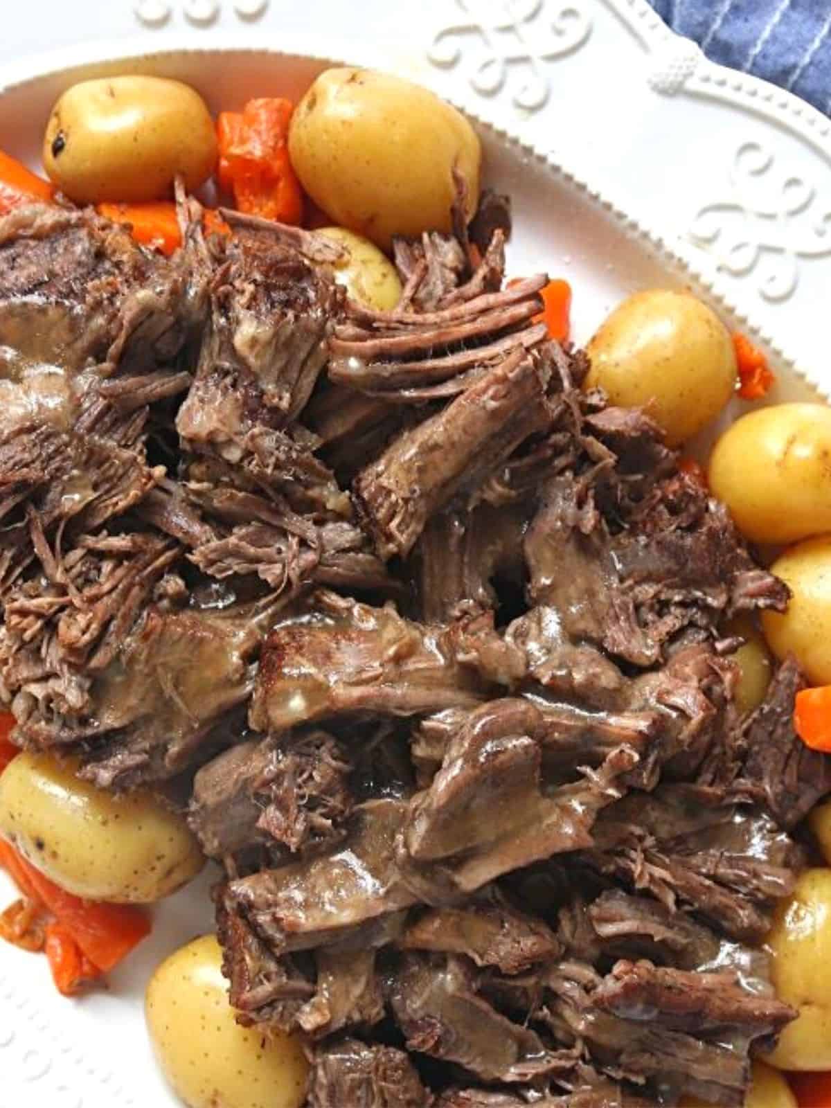 Pot Roast in white platter with potatoes and carrots next to Instant Pot.