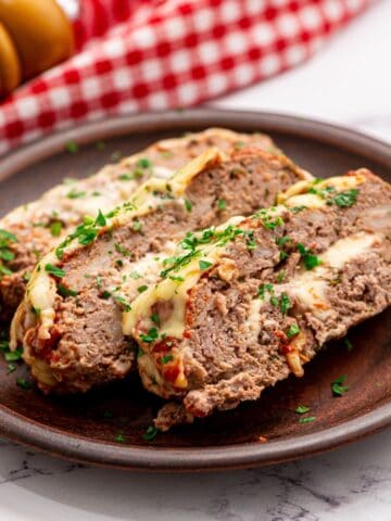 Sliced meatloaf on plate showing cheese stuffing.