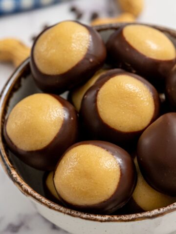 Close up of prepared peanut butter buckeyes in a bowl.