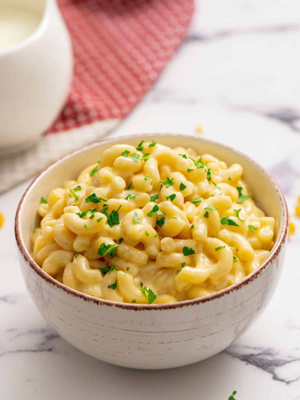 Bowl of stovetop white cheddar mac and cheese topped with parsley.