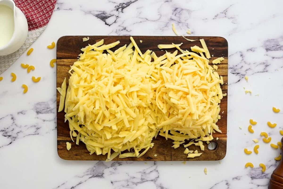 Freshly shredded cheese on wooden cutting board.