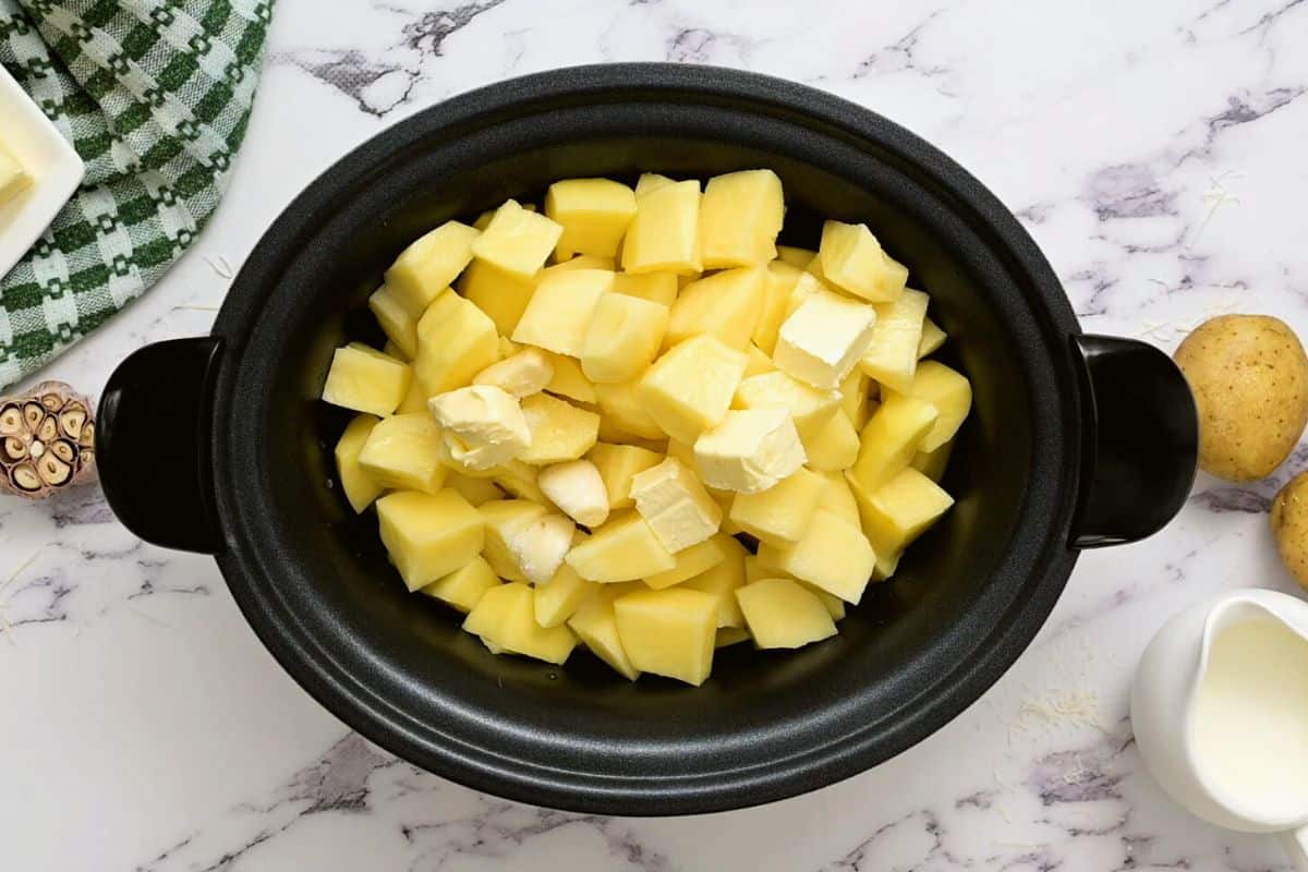 Cubed potatoes, butter, broth, and garlic in crockpot.