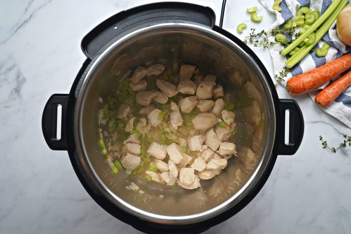 Sauteed chicken in inner pot simmering with wine.