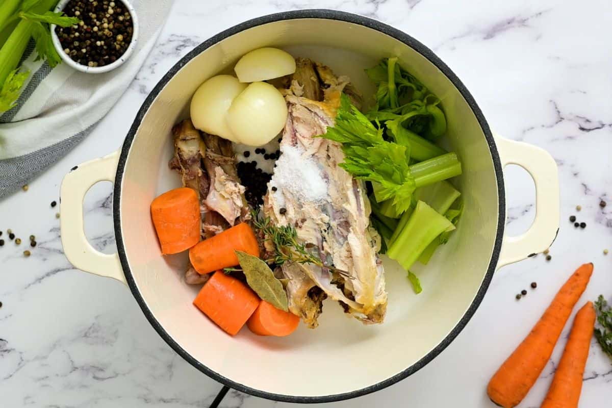 Chicken bones, carrots, celery, salt, bay leaves, and onion in stockpan.