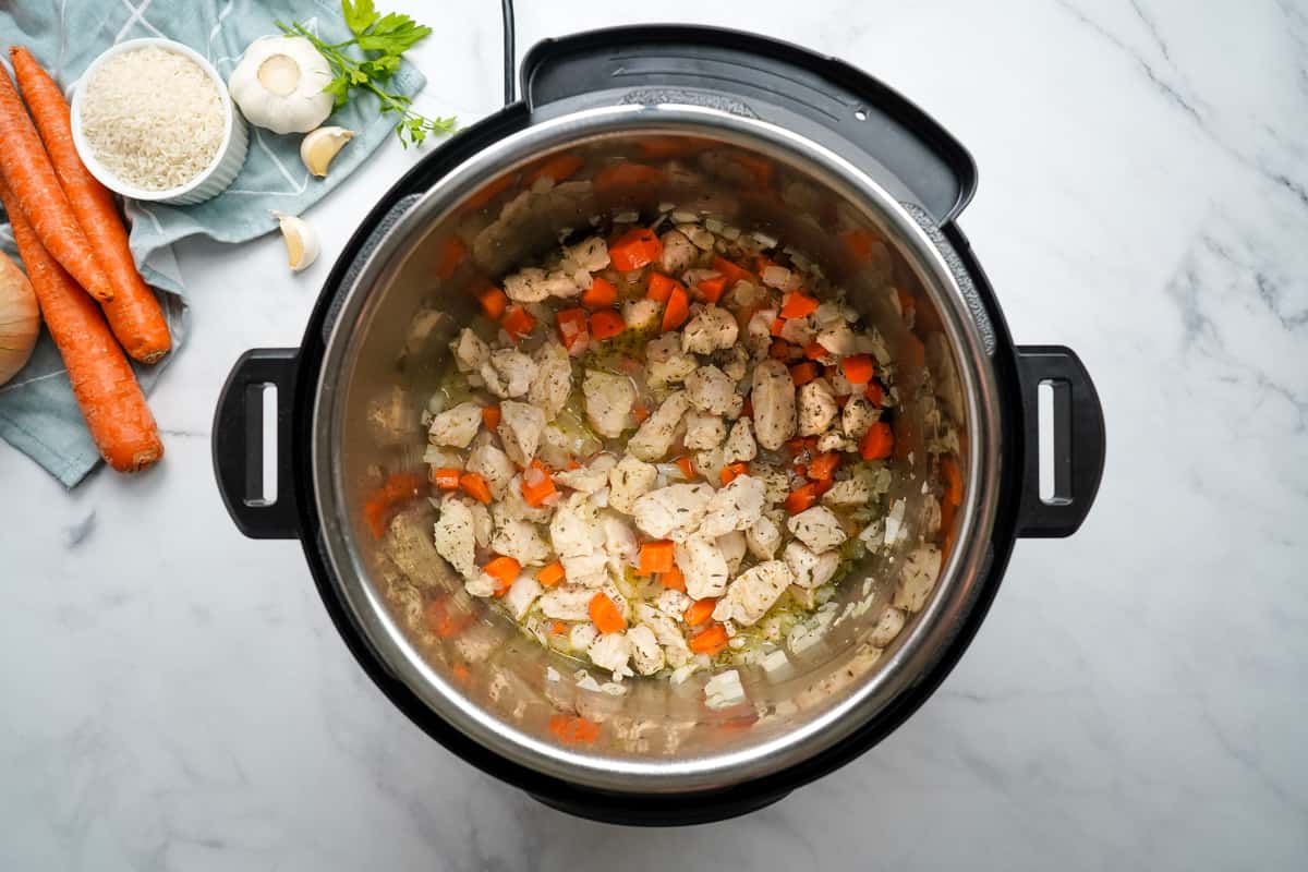 Sauteed chicken with carrots and onions in inner pot deglazed with white wine.