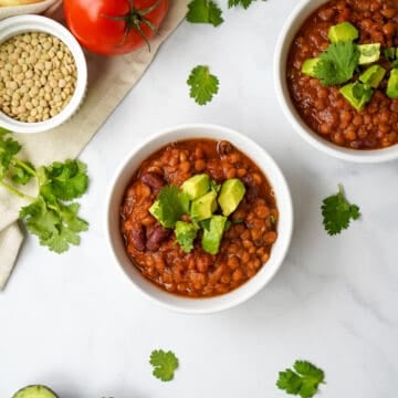 Instant Pot Lentil Chili in white bowl topped with diced avocado and cilantro.
