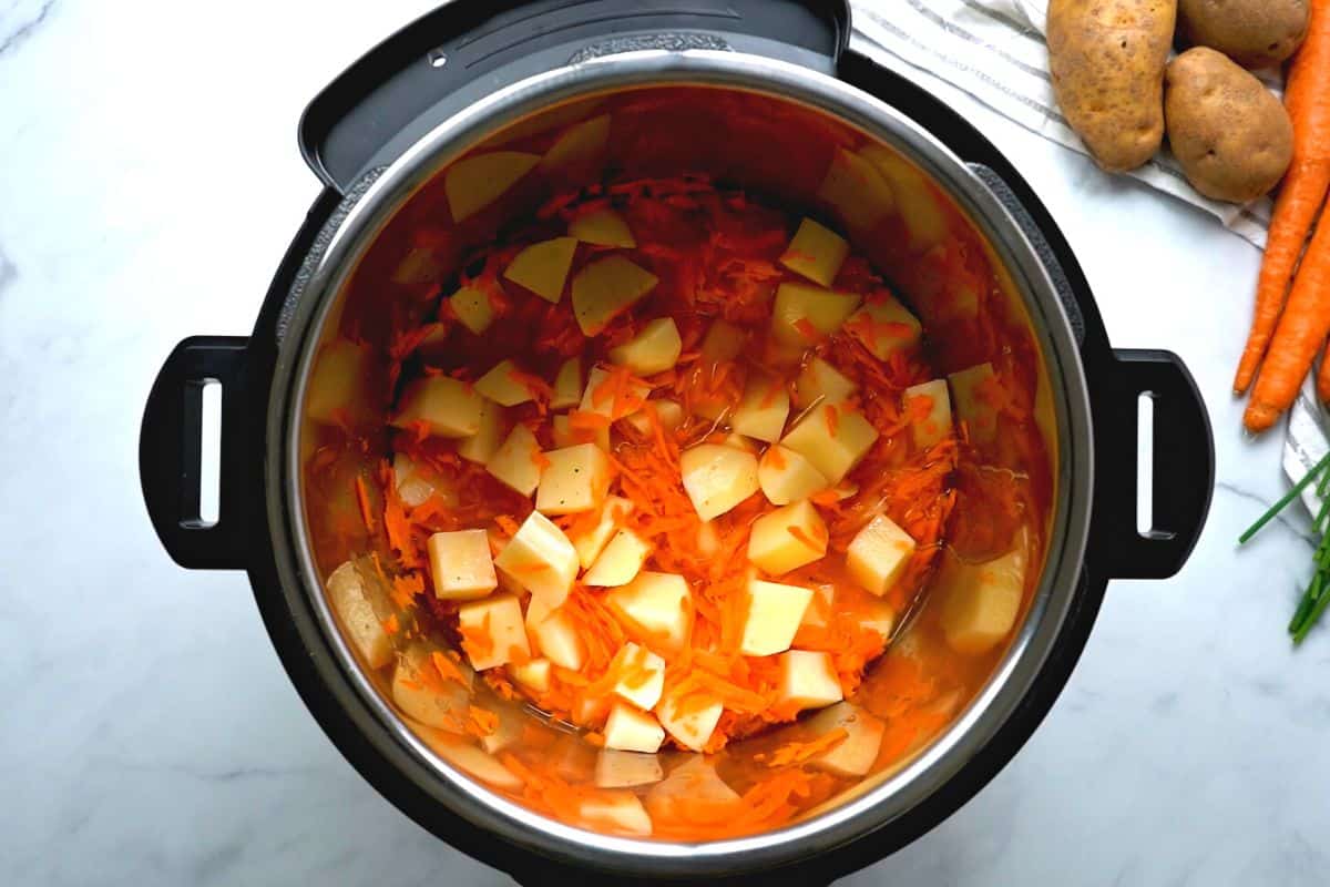 Carrots, broth, potatoes, and seasonings inside inner pot.