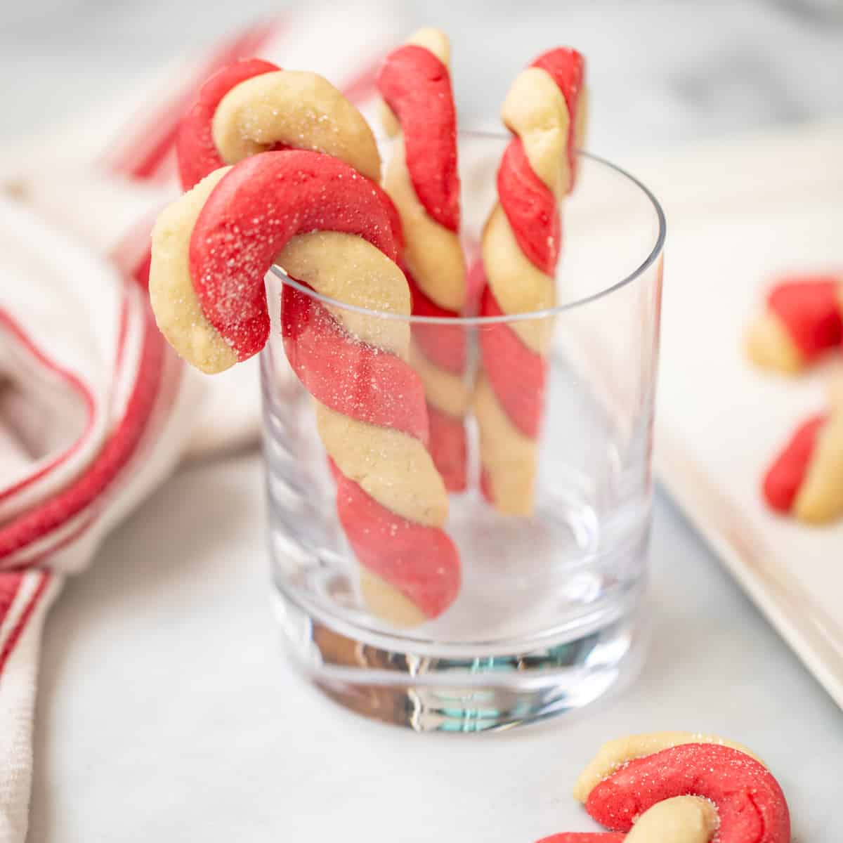 Candy Cane cookies hanging on a clear drinking glass.