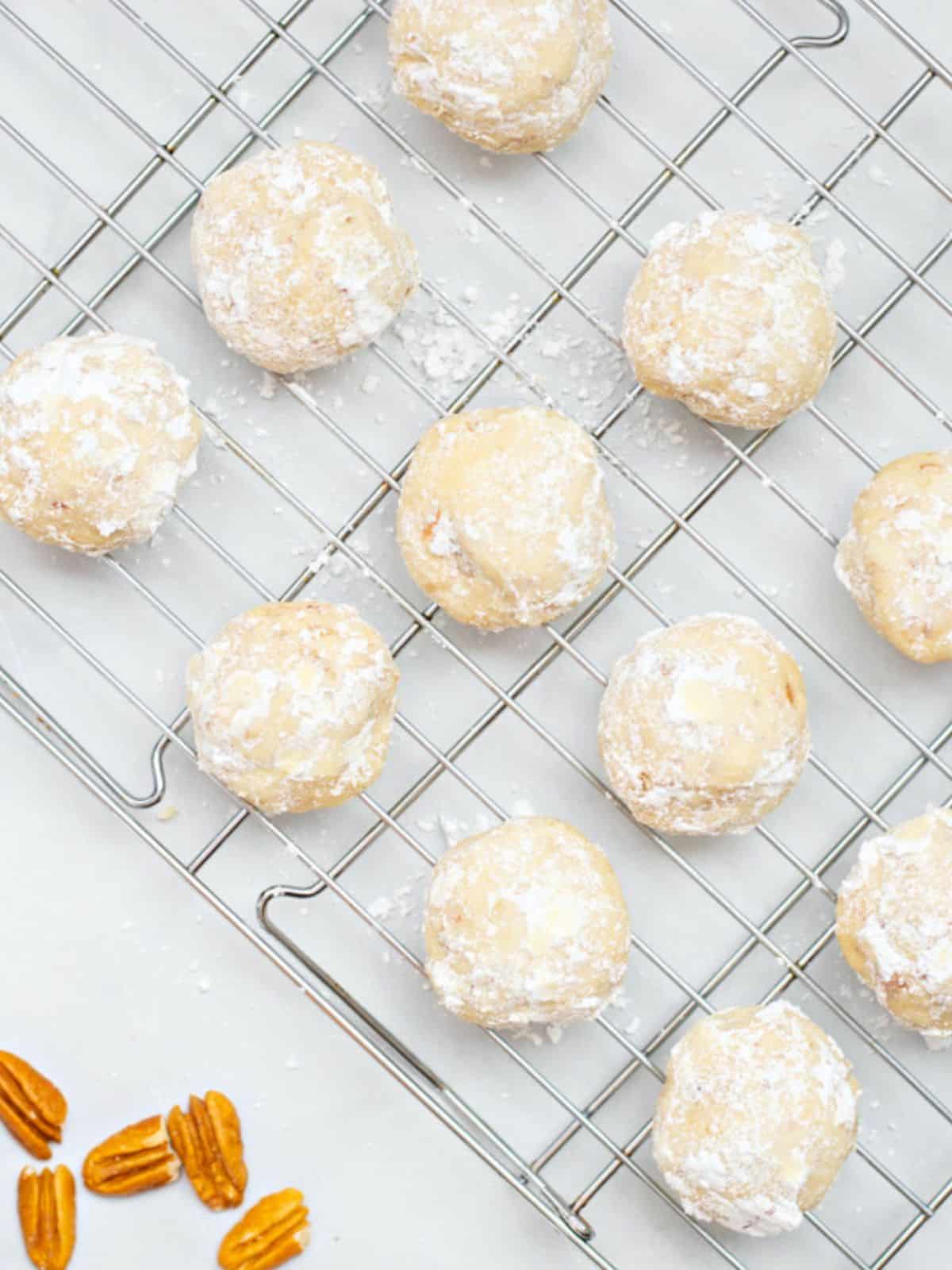 Snowball cookies after being rolled in powdered sugar on cooling rack.