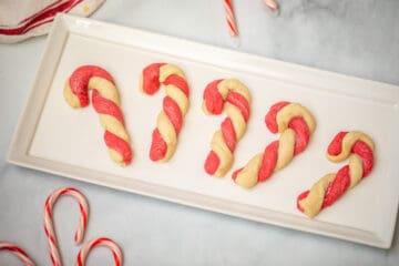 Tray of shaped candy cane cookies on white platter.