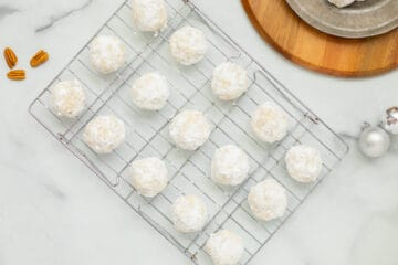 Snowball cookies after being rolled in powdered sugar on cooling rack.