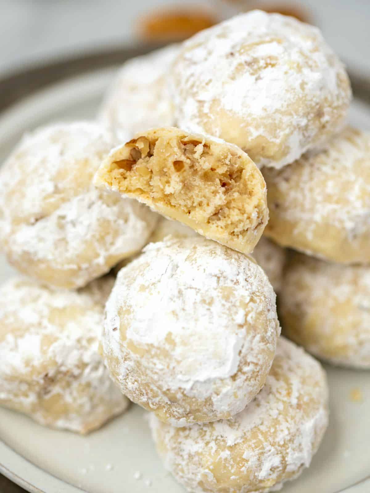 Snowball cookies on platter with one cut in half.