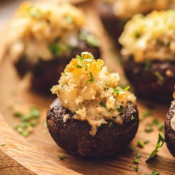Stuffed Mushrooms with sausage and breadcrumb topping on wooden serving platter.