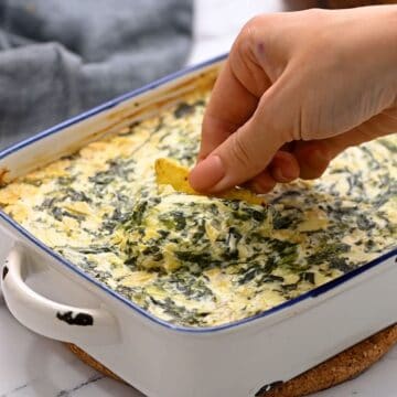 Chip scooping out spinach dip from baking dish.