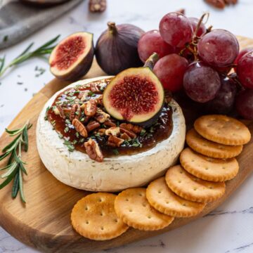 Baked Brie on cutting board topped with fig jam, walnuts, and fresh figs.
