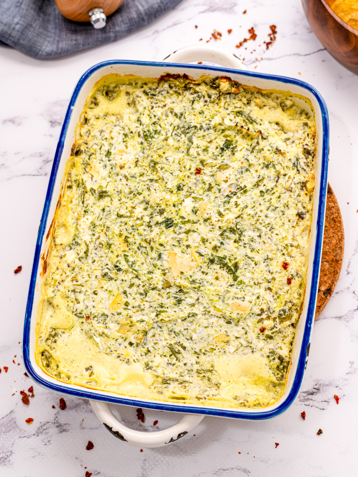 Baked Spinach Artichoke Dip in white baked dish.