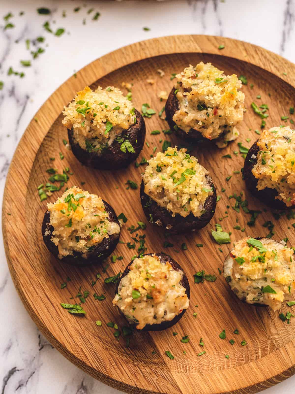 Stuffed Mushrooms with sausage and breadcrumb topping on wooden serving platter.