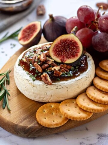 Baked Brie on cutting board topped with fig jam, walnuts, and fresh figs.