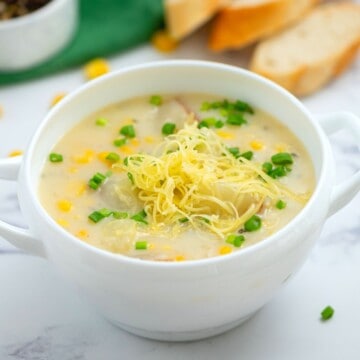 Bowl of Potato Corn Chowder topped with sharp white cheddar and chives.