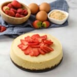 Instant Pot Cheesecake topped with sliced strawberries and berries in background.