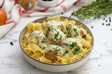 Bowl of turkey swedish meatballs served over egg noodles and topped with parsley.
