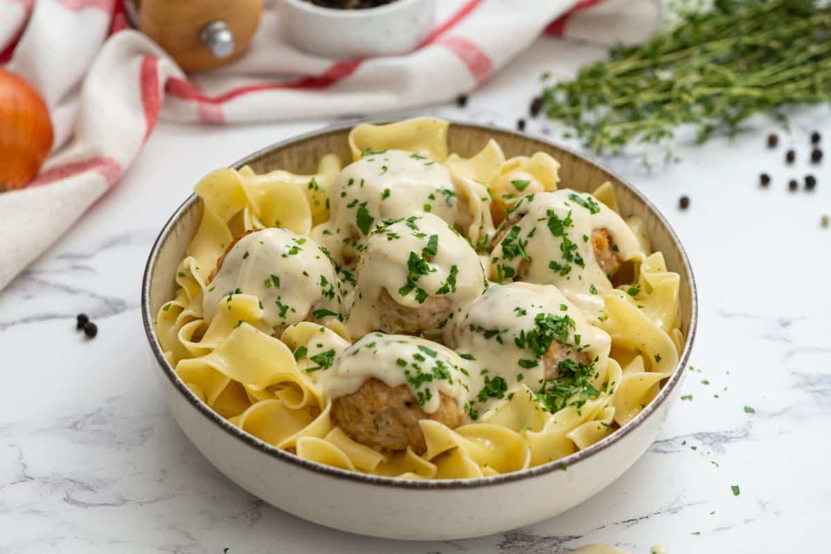 Bowl of turkey swedish meatballs served over egg noodles and topped with parsley.