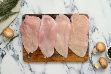 Chicken breasts cut in half and pounded on cutting board.