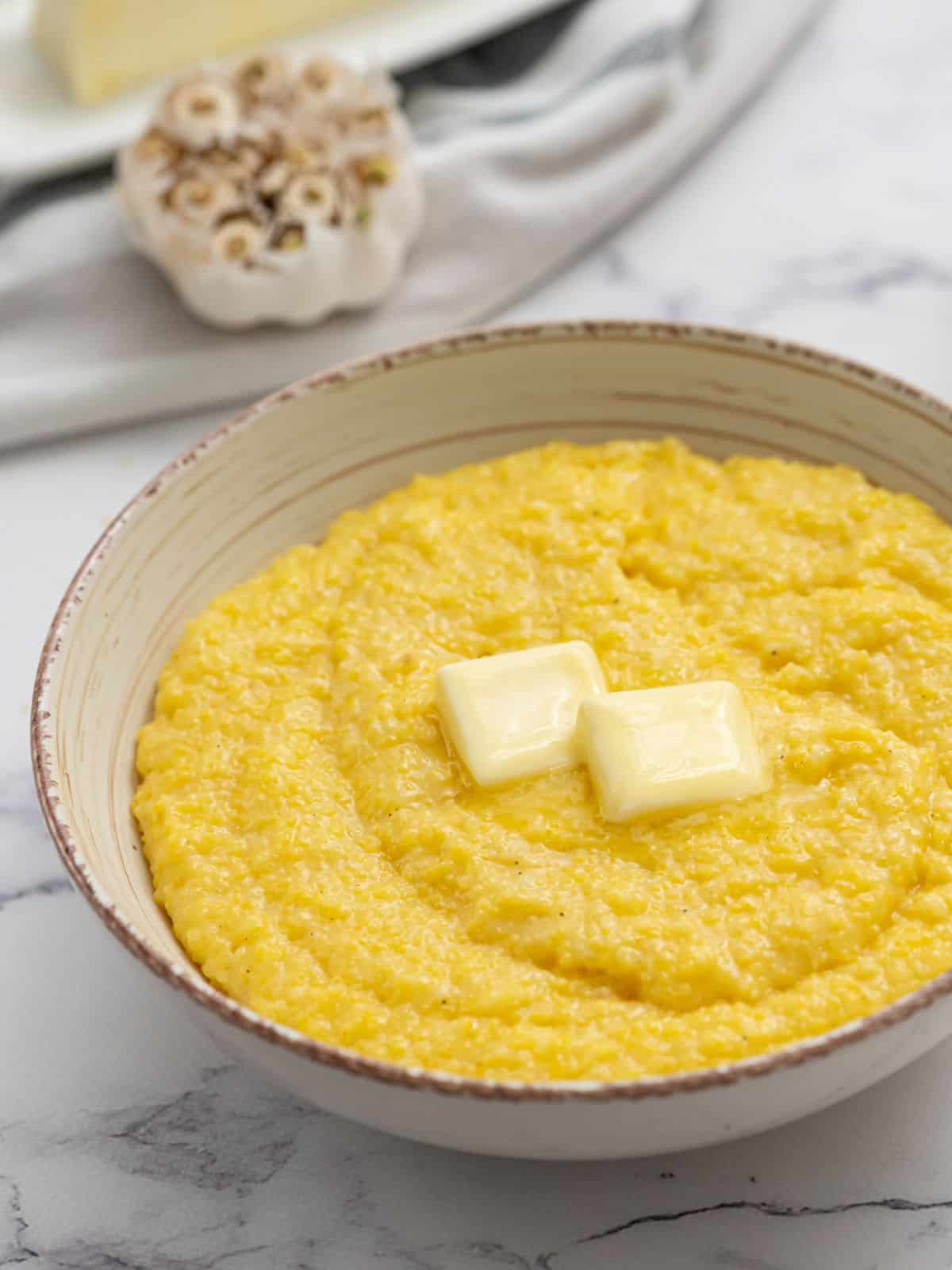 Bowl of cheese grits topped with butter.