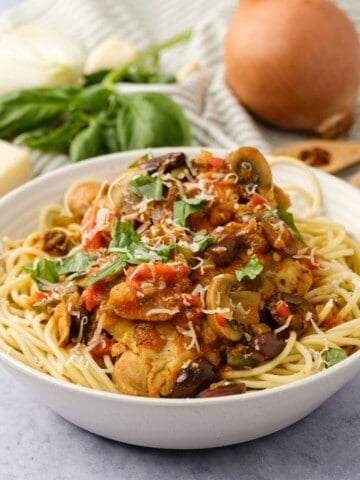 Instant Pot Chicken Cacciatore served on top of spaghetti noodles topped with parmesan and basil.