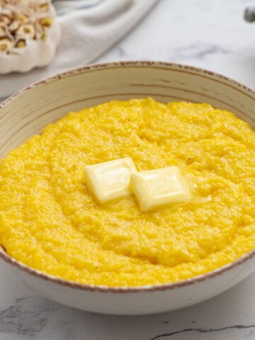 Bowl of creamy grits topped with 2 pats of butter.