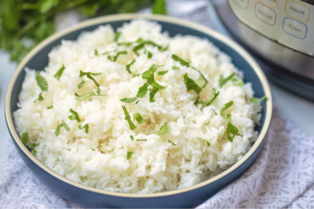Bowl of white rice topped with parsley next to Instant Pot.