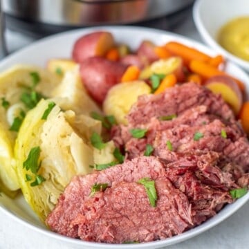 Corned Beef and Cabbage on White Platter with Potatoes and Carrots.
