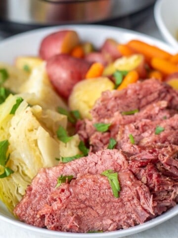 Corned Beef and Cabbage on White Platter with Potatoes and Carrots.