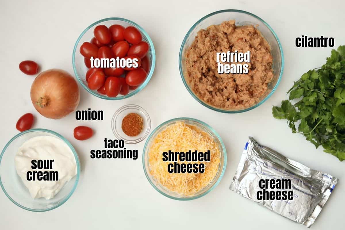 Ingredients for taco dip labeled on counter. 