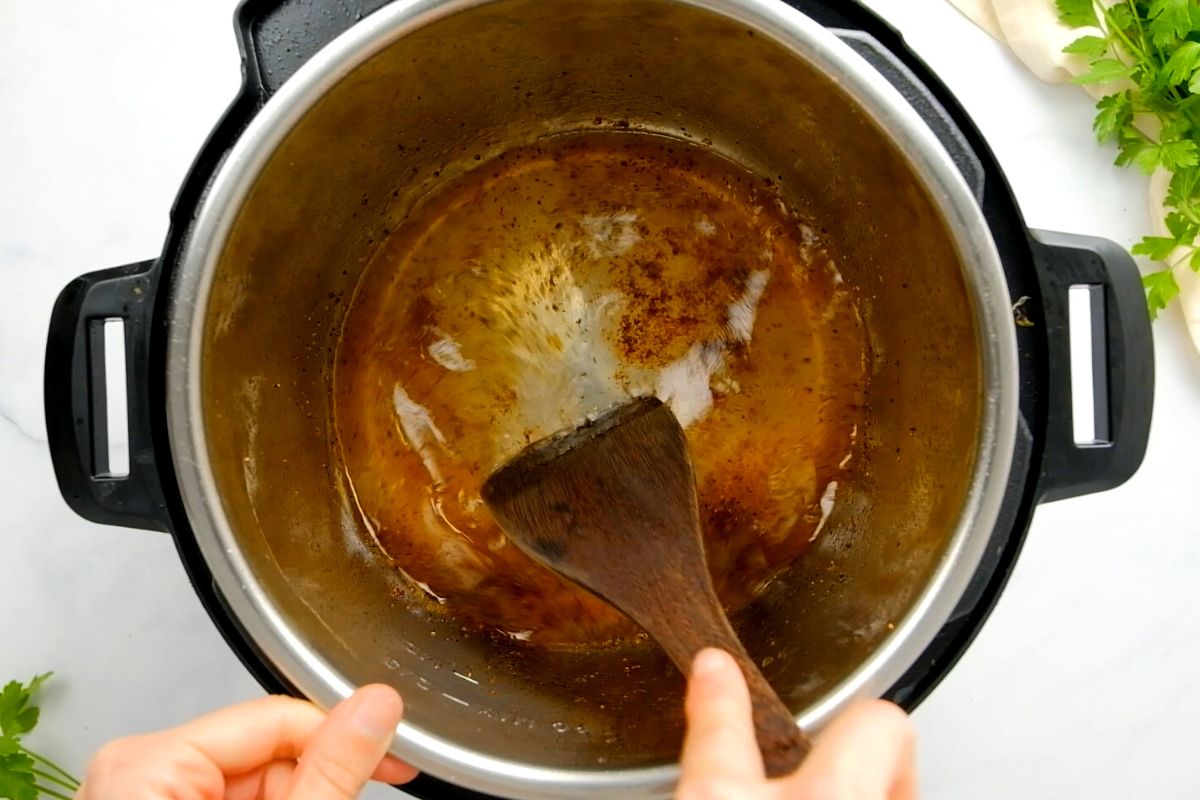 Wooden spoon scraping bottom of inner pot.