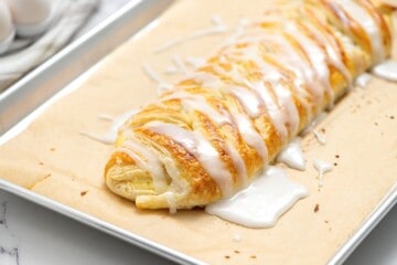 Glazed puff pastry cream cheese danish on baking sheet.