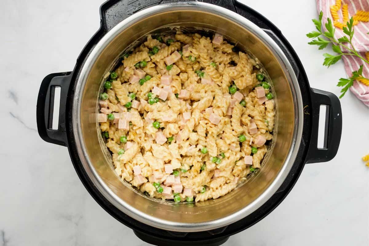 Instant Pot with cooked noodles, peas, and ham.