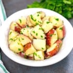 Bowl of buttered red potaotes topped with parsley.