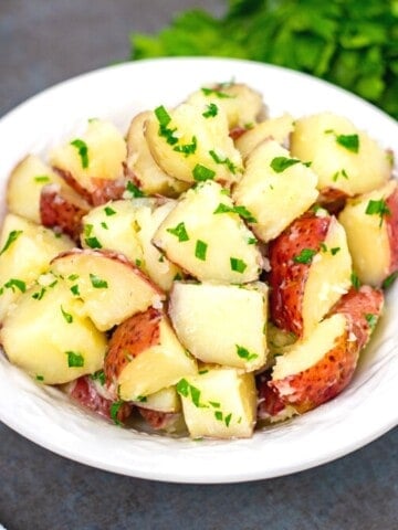 Bowl of buttered red potaotes topped with parsley.