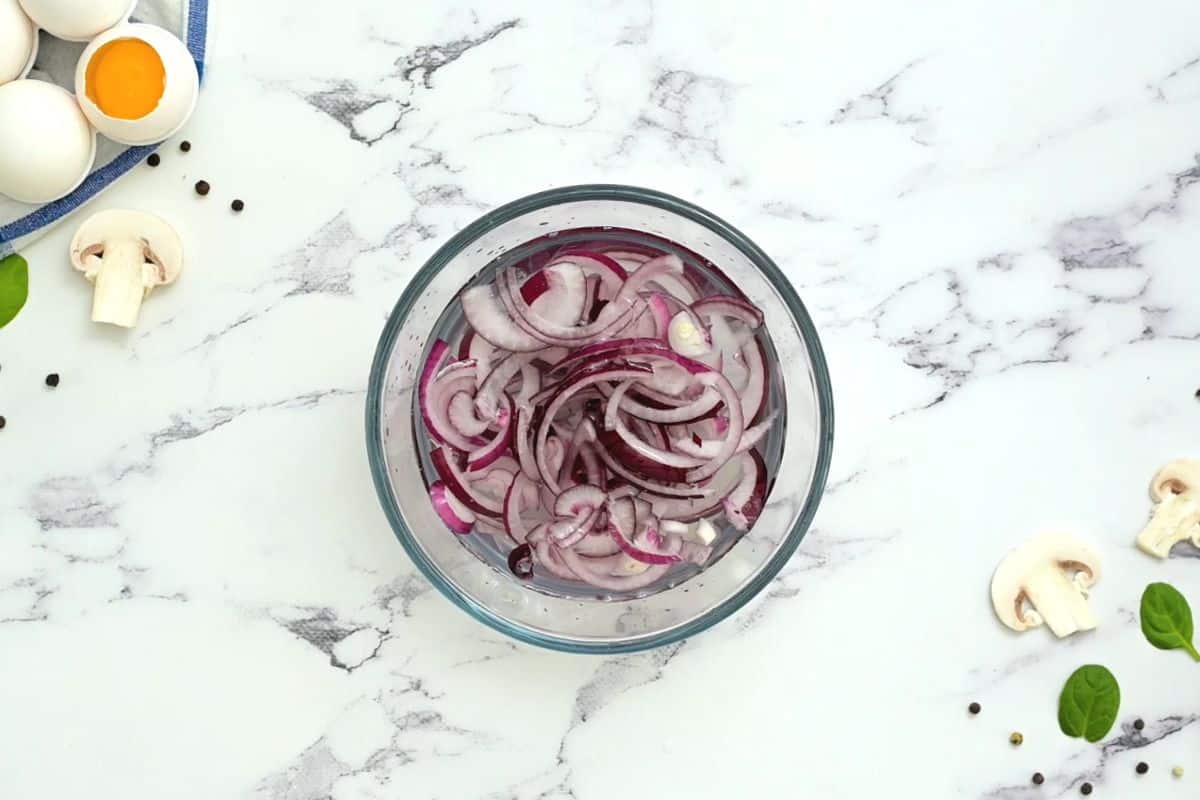 sliced red onions soaking in water in small bowl.