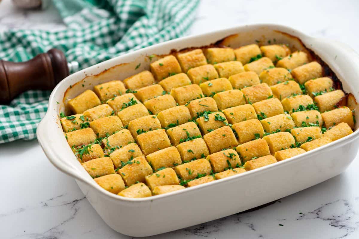 Baked Tater Tot Casserole in white casserole dish and topped with parsley.