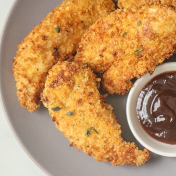 Crispy Air Fryer Chicken Tenders on a gray plate next to BBQ sauce.