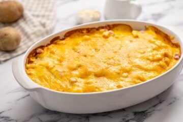 White baking dish with scalloped potatoes, ham and cheese.
