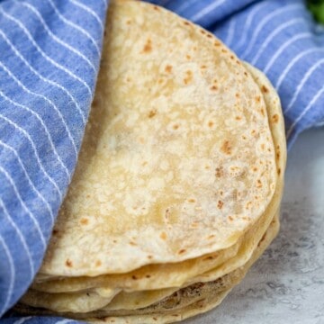 Flour tortillas wrapped in a blue kitchen towel.