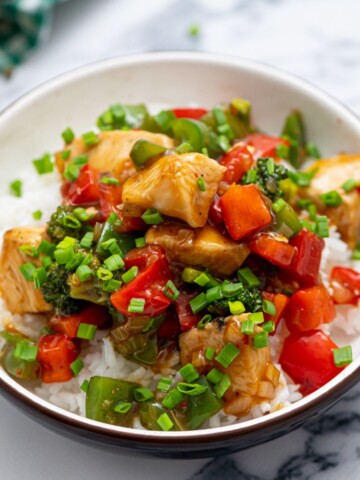 Bowl of Homemade Hunan Chicken served over rice and topped with minced green onion.