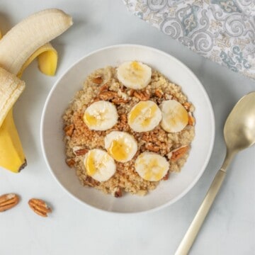 Bowl of Quinoa Porridge topped with sliced banana and pecans.
