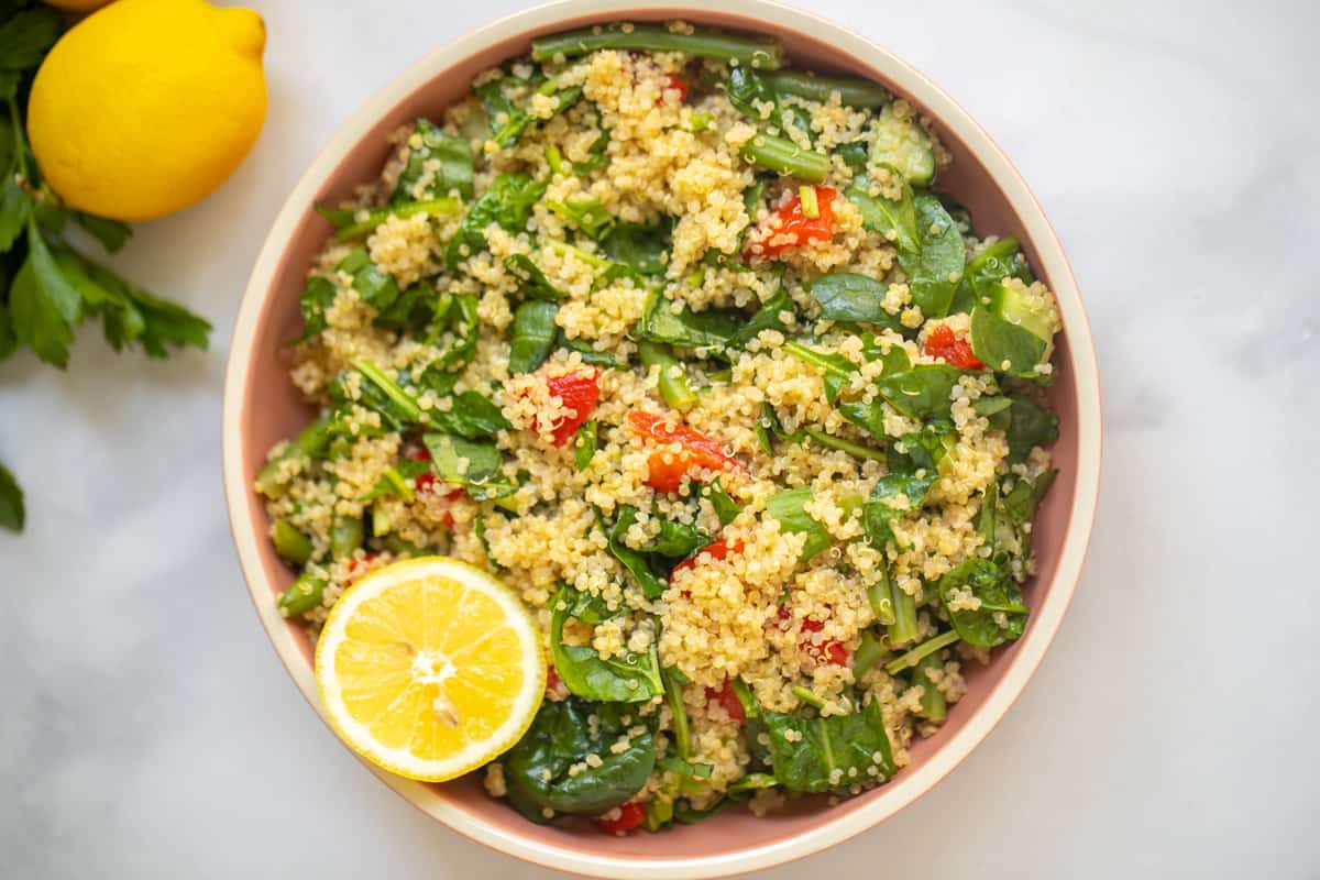 Bowl of Quinoa Salad with spinach, roasted red peppers, and lemon.