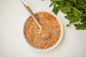 Homemade dry rub mixed together in small white bowl with a silver spoon.
