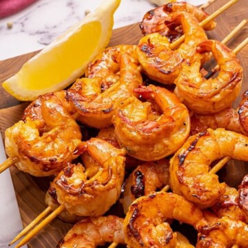 Photo of grilled shrimp next to lemon wedge.