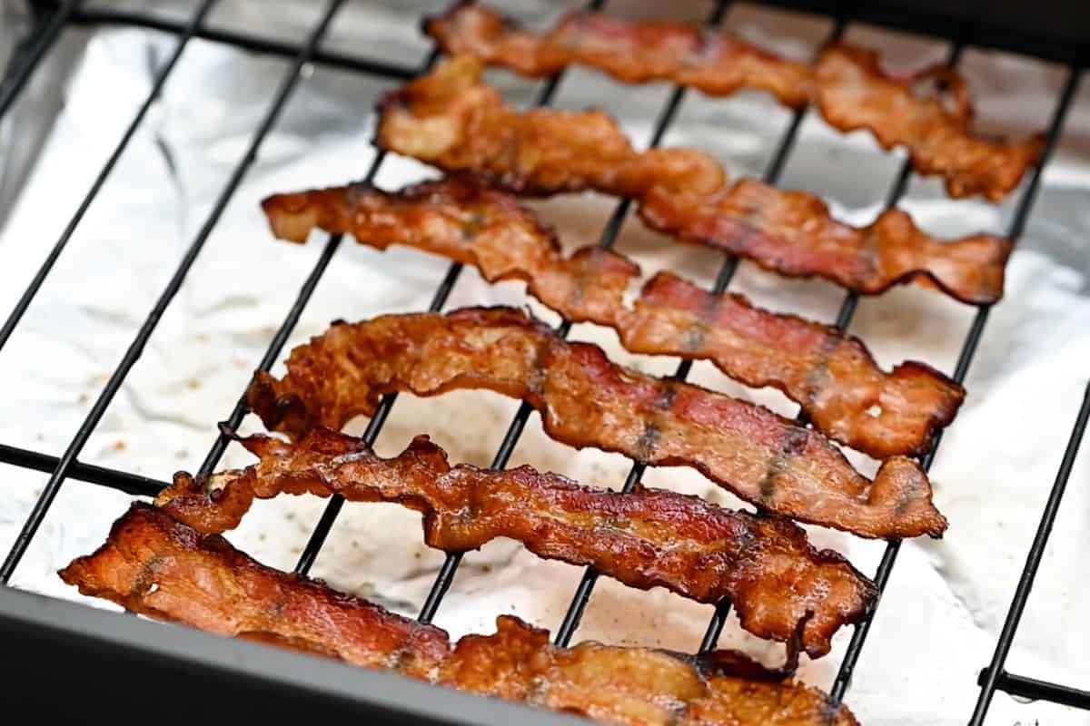 Baked bacon slices on oven rack.